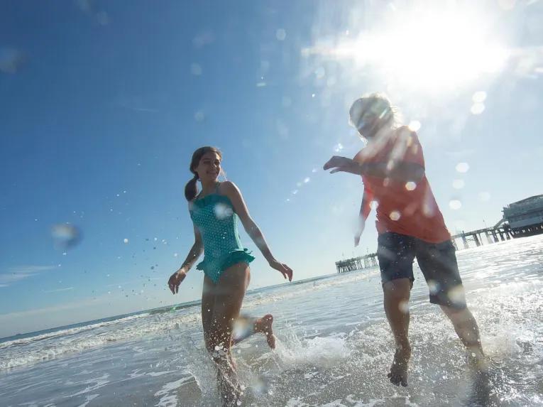 Two kids playing and splashing in the ocean waves at Daytona Beach on a sunny day.